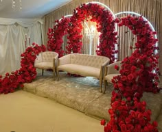 a living room decorated with red flowers and white couches in front of a mirror