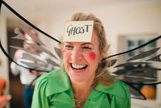 a woman with her face painted like a fairy holding up a piece of paper that says ghost