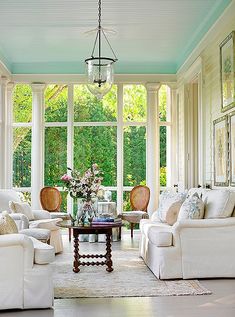 a living room filled with white furniture and lots of windows covered in blue tints