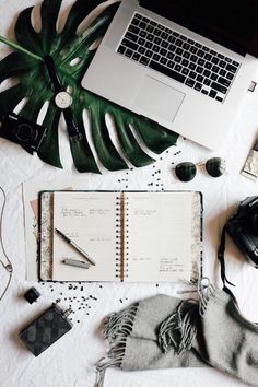 an open notebook sitting on top of a table next to a laptop