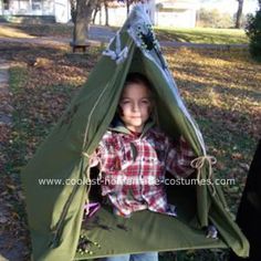 a young boy is standing outside in a teepee