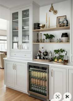 a kitchen with white cabinets and shelves filled with bottles, glasses, and other items