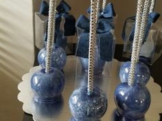 three blue vases with crystal balls in them sitting on a white plate and some bows