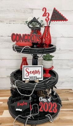 a three tiered cake with red and black decorations on the top, along with a sign that says congrats