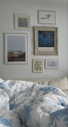 a bed with blue and white comforter next to pictures on the wall