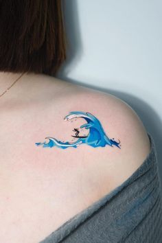 a woman with a blue wave tattoo on her shoulder