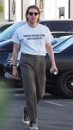 a man walking across a parking lot wearing a t - shirt