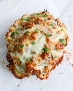 a close up of a pizza on a piece of paper with cheese and green onions