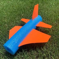 an orange and blue toy airplane sitting in the grass