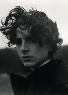 a young man with curly hair wearing a suit