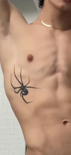 a shirtless man with a spider tattoo on his chest and hand in the air