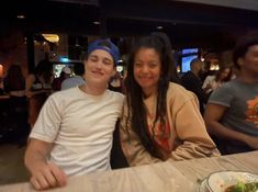 two people sitting at a table with plates of food in front of them and smiling for the camera