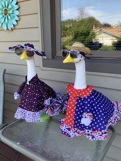 two ducks wearing sun glasses sitting on top of a metal table next to a window