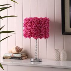 a lamp that is on top of a table next to some books and a potted plant