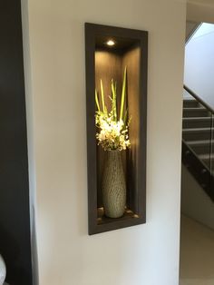 there is a vase with flowers in it sitting on the wall next to some stairs