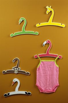 three baby onesuits and two hangers on a yellow wall with giraffes