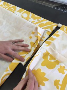 two hands are working on fabric with yellow and white designs