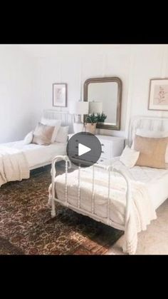 a white bedroom with two beds and a rug on the floor in front of it