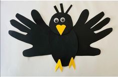 a paper cut out of a black bird with yellow feet