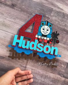 someone is holding up the number four for their thomas the train birthday cake topper