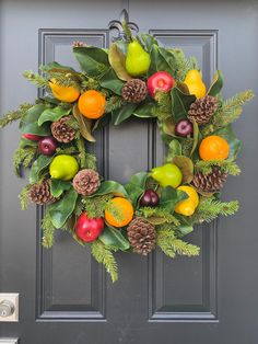 a wreath with fruit and pine cones on the front door