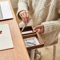 a person sitting at a desk with a pen and pencil in their lap top box