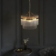 a chandelier hanging from the ceiling in a dark room with a table and chair