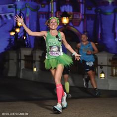 a woman in a green tutu skirt running down a street at night with other people behind her