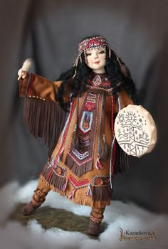 a doll dressed in native american clothing holding a frisbee with writing on it