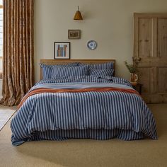 a bed with blue and orange striped comforter in a bedroom next to a window