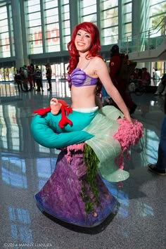 a woman dressed as ariel from the little mermaid is posing for a photo in an airport