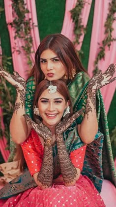 two women sitting on top of each other with their hands covered in hendi tattoos