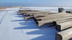 a row of wooden benches sitting on top of snow covered ground