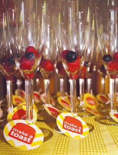 there are many wine glasses with berries in them on the tablecloth and one has a sticker that says make toast