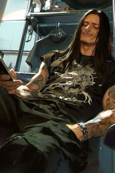 a man with long hair and tattoos sitting in a chair looking at his cell phone