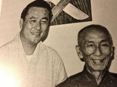 an old black and white photo of two men in front of a wall with scissors