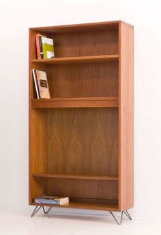 a wooden bookcase with three shelves and two books on the top one is empty