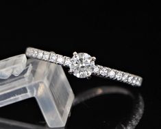 a diamond engagement ring sitting on top of a clear object