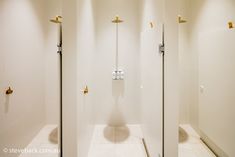 two white stalls with gold handles in a bathroom