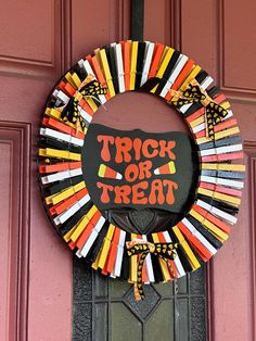 a trick or treat wreath is hanging on the front door with candy sticks around it