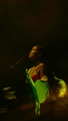 a woman sitting in a green chair next to a microphone on a stage with her head tilted back