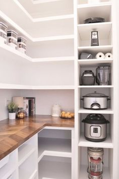 an organized pantry with white shelves and wooden counter tops