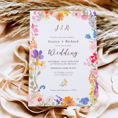 a wedding card with flowers on it sitting on top of a white cloth covered bed