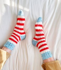 two feet with red, white and blue socks laying on a bed