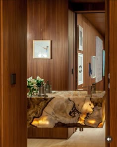 a bathroom with marble counter tops and wooden walls, along with an open door leading to another room