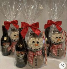 three wine bottles wrapped in clear plastic and decorated with snowmen, candy canes and bows