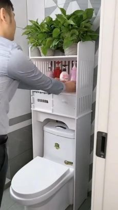 a man standing in front of a toilet next to a plant on top of a shelf