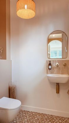 a white toilet sitting next to a bathroom sink under a round light fixture in a bathroom