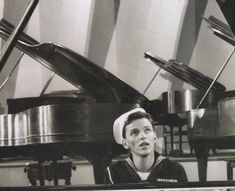 a young boy wearing a sailor's hat sitting at a piano