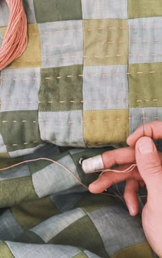 someone is stitching something on the side of a quilt with a needle and thread